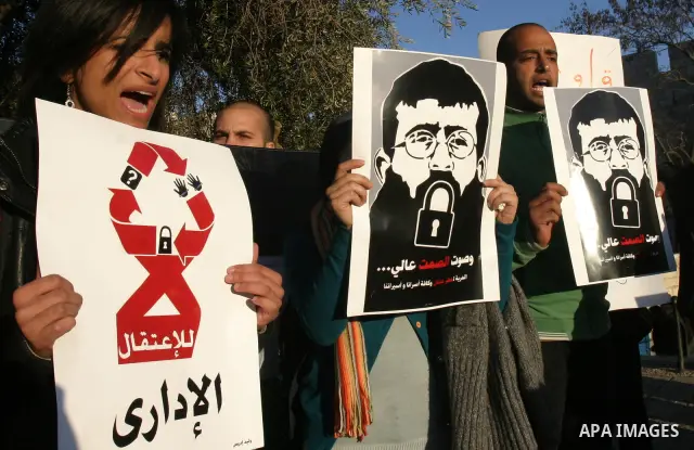 Palestinians holds a poster with a drawing depicting Islamic Jihad member Khader Adnan with a locked mouth, who has been on hunger strike for two months, during a demonstration in Jerusalem, Tuesday, Feb. 21, 2012. Adnan...