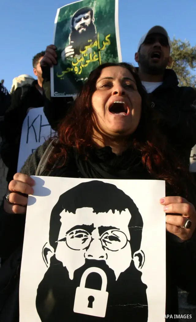 Palestinians holds a poster with a drawing depicting Islamic Jihad member Khader Adnan with a locked mouth, who has been on hunger strike for two months, during a demonstration in Jerusalem, Tuesday, Feb. 21, 2012. Adnan...