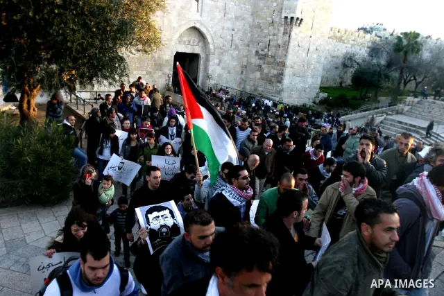 Palestinians holds a poster with a drawing depicting Islamic Jihad member Khader Adnan with a locked mouth, who has been on hunger strike for two months, during a demonstration in Jerusalem, Tuesday, Feb. 21, 2012. Adnan...