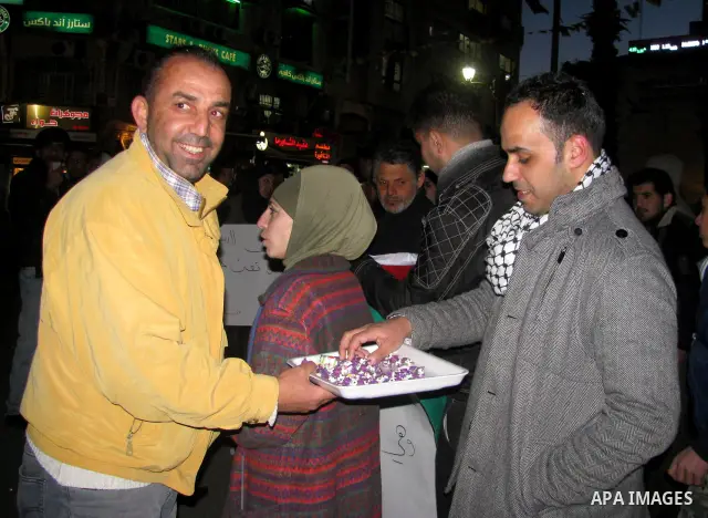 Palestinians distribute sweets to celebrate the Israeli court decision to release Islamic Jihad member Khader Adnan from prison, in the West Bank city of Ramallah, Tuesday, Feb. 21, 2012. Adnan agreed to end his 66-day h...