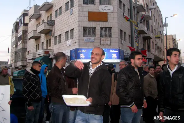 Palestinians distribute sweets to celebrate the Israeli court decision to release Islamic Jihad member Khader Adnan from prison, in the West Bank city of Ramallah, Tuesday, Feb. 21, 2012. Adnan agreed to end his 66-day h...