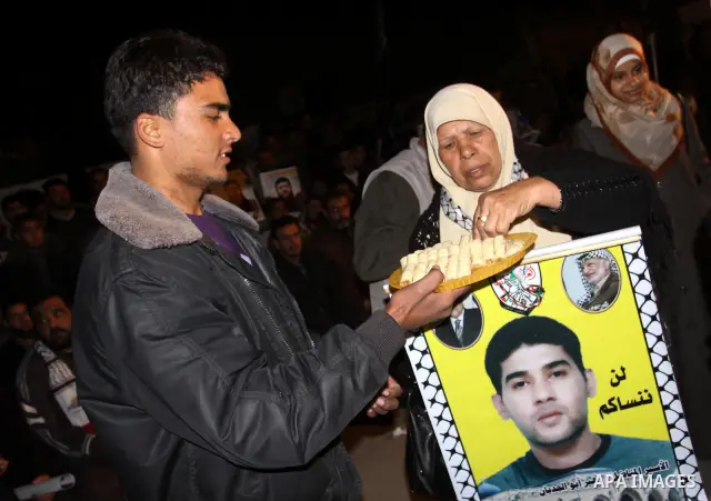 Palestinians celebrate the Israeli court decision to release Islamic Jihad member Khader Adnan from prison, in front of the Red Cross headquarters in Gaza city, Tuesday, Feb. 21, 2012. Adnan agreed to end his 66-day hung...