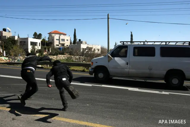 Palestinian youth throw stones at a vehicle driven by an Israeli settler along Route 60 to a Jewish settlement which passes close to the village of Beit Omar in the Israeli occupied West Bank, on February 21, 2012. Stone...