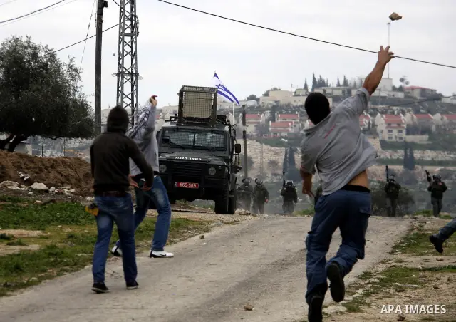 A Palestinian protester throws stones at Israeli soldiers during a demonstration against the expropriation of Palestinian land by Israel in the village of Kfar Qaddum, near the West Bank city of Nablus, on February 24, 2...