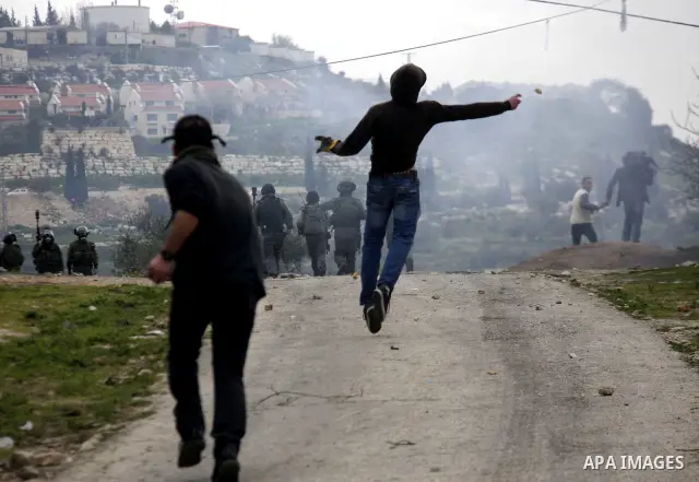 A Palestinian protester throws stones at Israeli soldiers during a demonstration against the expropriation of Palestinian land by Israel in the village of Kfar Qaddum, near the West Bank city of Nablus, on February 24, 2...