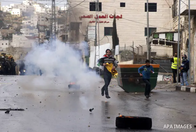 An Israeli policeman fires a tear gas canister during clashes with Palestinian protesters at a demonstration against the closure of Shuhada street to Palestinians, in the West Bank city of Hebron February 24, 2012. Some...