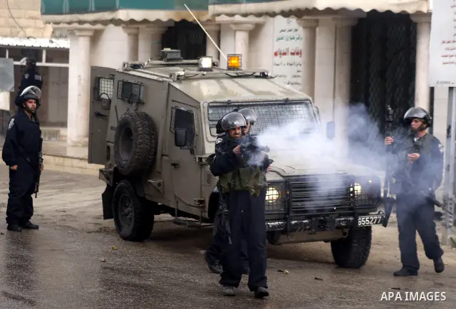 An Israeli policeman fires a tear gas canister during clashes with Palestinian protesters at a demonstration against the closure of Shuhada street to Palestinians, in the West Bank city of Hebron February 24, 2012. Some...