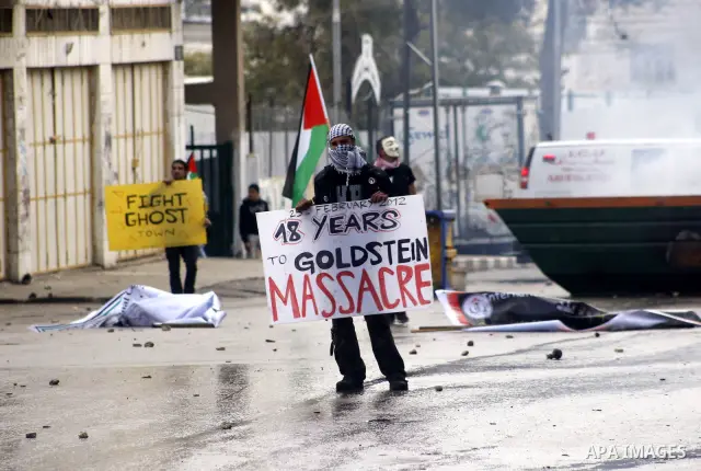 A Palestinian protester holds a placard during a demonstration against the closure of Shuhada street to Palestinians, in the West Bank city of Hebron February 24, 2012. Some 200 protesters, including foreign and Israeli...