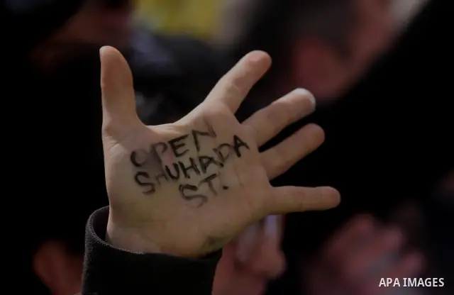 A Palestinian protester holds a placard during a protest against the closure of Shuhada street to Palestinians, in the West Bank city of Hebron February 24, 2012. Some 200 protesters, including foreign and Israeli activi...