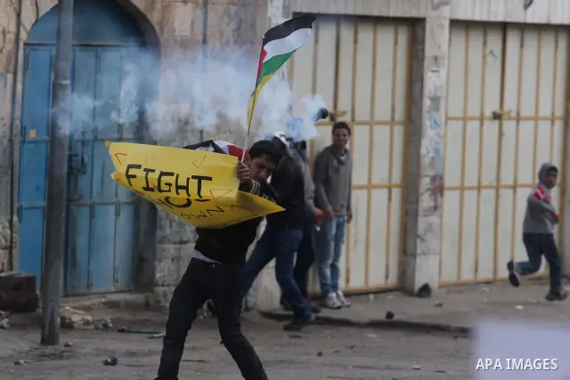 A Palestinian protester holds a placard during a protest against the closure of Shuhada street to Palestinians, in the West Bank city of Hebron February 24, 2012. Some 200 protesters, including foreign and Israeli activi...