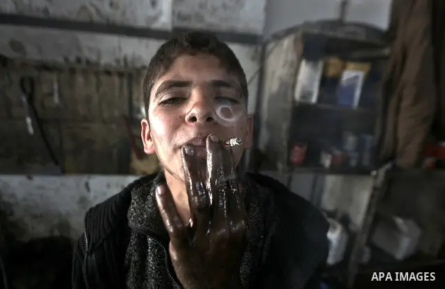 Palestinian 11 year old Anis, smoking a cigarette, while repairing a customers car in the town of Beit Lahyia in northern Gaza on 23 February 2012. Reports state that child labor is widespread in the Gaza Strip because o...