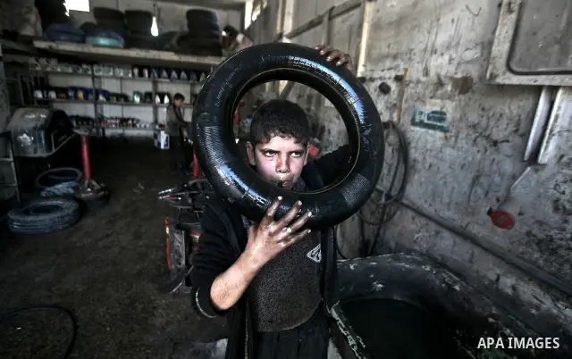 Palestinian 11 year old Anis, inflates an inner tube while repairing a customers car in the town of Beit Lahyia in northern Gaza on 23 February 2012. Reports state that child labor is widespread in the Gaza Strip because...