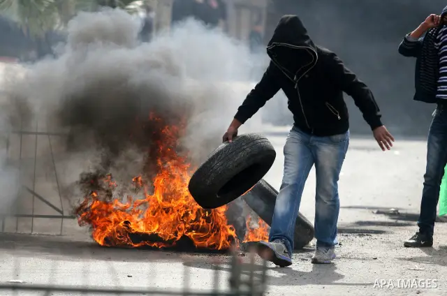 Palestinian stone throwers burn tires durign clashes with Israeli soldiers in the West Bank neighbourhood of Al-Ram, adjacent to Israeli-annexed east Jerusalem, on February 25, 2012. At least nine Palestinians were injur...