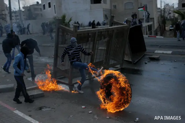 Palestinian stone throwers burn tires durign clashes with Israeli soldiers in the West Bank neighbourhood of Al-Ram, adjacent to Israeli-annexed east Jerusalem, on February 25, 2012. At least nine Palestinians were injur...