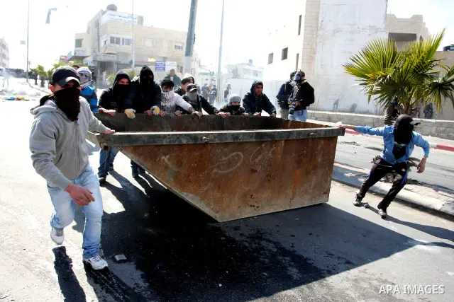 Masked Palestinian protesters run away from tear gas fired by Israeli security forces, not pictured, during clashes in the West Bank town of Al-Ram, near Jerusalem, Saturday, Feb. 25, 2012. Clashes erupted after the fune...