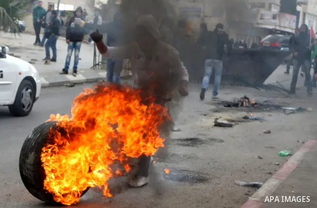 Palestinian stone throwers burn tires durign clashes with Israeli soldiers in the West Bank neighbourhood of Al-Ram, adjacent to Israeli-annexed east Jerusalem, on February 25, 2012. At least nine Palestinians were injur...