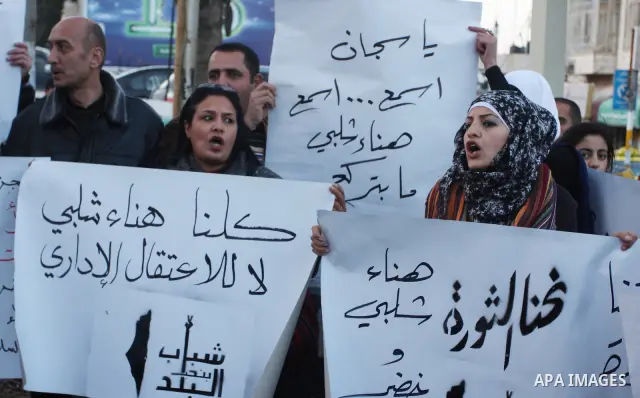 Palestinians hold up banners for Hana Al-Shalabi, a Palestinian prisoner on hunger strike jailed in Israel, as they protest against Israel's policy of administrative detention, in the West Bank city of Ramallah , Monday,...