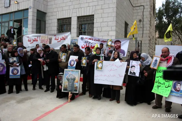 Palestinians hold a picture for Hana Al-Shalabi, a Palestinian prisoner on hunger strike jailed in Israel, as they protest against Israel's policy of administrative detention, in the West Bank city of Ramallah , Monday,...