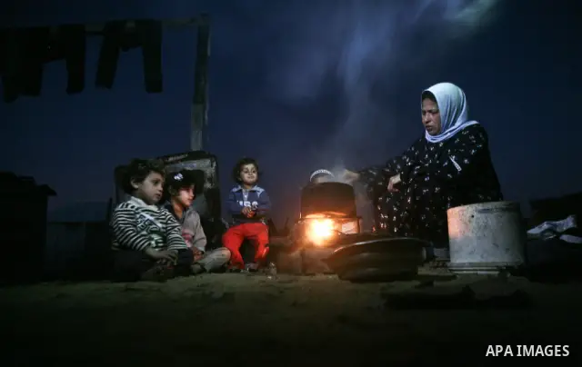 A Palestinian mother cooks on firewood at their house inbetween makeshift tents in one of the most poor regions in Al-Nusirat neighborhood, central Gaza Strip on 28 February 2012. The United Nations Relief and Works Agen...