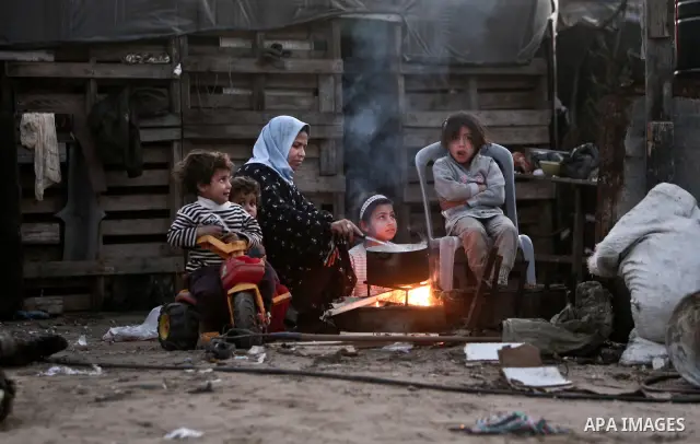 A Palestinian mother cooks on firewood at their house inbetween makeshift tents in one of the most poor regions in Al-Nusirat neighborhood, central Gaza Strip on 28 February 2012. The United Nations Relief and Works Agen...