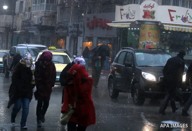 Palestinians walk in a street during the heavy rain and cold winds in the West Bank city of Ramallah on 29 Feb, 2012. Photo by Issam Rimawi