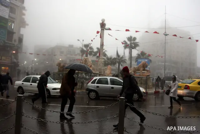 Palestinians walk in a street during the heavy rain and cold winds in the West Bank city of Ramallah on 29 Feb, 2012. Photo by Issam Rimawi