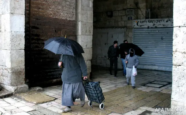 Palestinians walk in a street during the heavy rain and cold winds in Jerusalem's Old City, on Mar. 01, 2012. Photo by Mahfouz Abu Turk