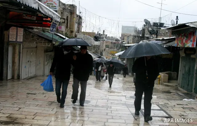Palestinians walk in a street during the heavy rain and cold winds in Jerusalem's Old City, on Mar. 01, 2012. Photo by Mahfouz Abu Turk
