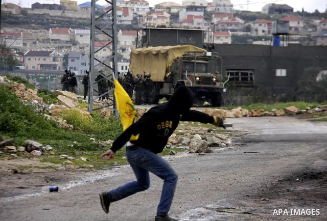A Palestinian protester throws stones at Israeli soldiers during a demonstration against the expropriation of Palestinian land by Israel in the village of Kfar Qaddum, near the West Bank city of Nablus, on March 2, 2012....