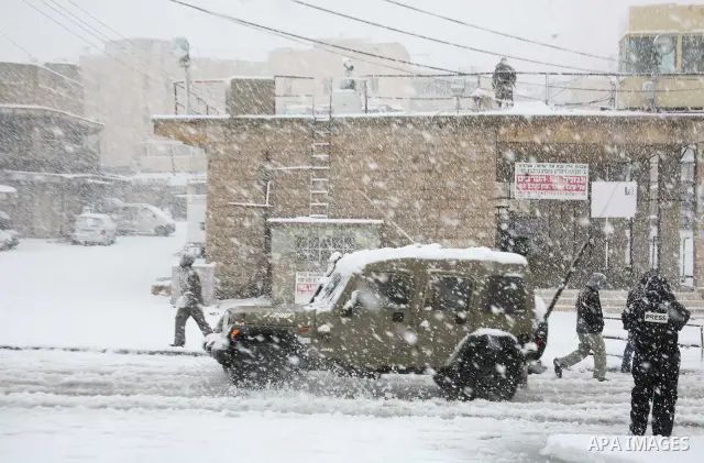 Palestinian youths throw snowballs as they play next to Israeli army position in the West Bank city of Hebron as wintry weather swept through the region on March 2, 2012. Photo by Mamoun Wazwaz