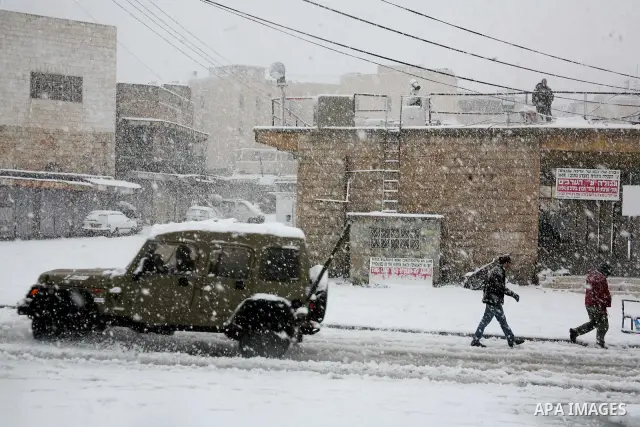 Palestinian youths throw snowballs as they play next to Israeli army position in the West Bank city of Hebron as wintry weather swept through the region on March 2, 2012. Photo by Mamoun Wazwaz