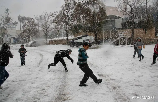 Palestinian youths throw snowballs as they play next to Israeli army position in the West Bank city of Hebron as wintry weather swept through the region on March 2, 2012. Photo by Mamoun Wazwaz