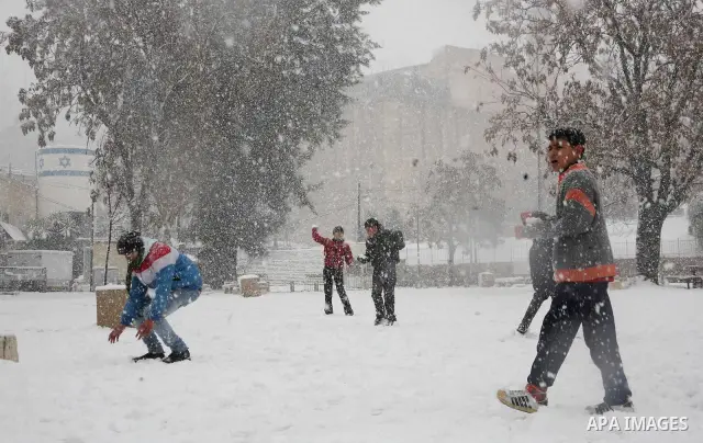 Palestinian youths throw snowballs as they play next to Israeli army position in the West Bank city of Hebron as wintry weather swept through the region on March 2, 2012. Photo by Mamoun Wazwaz