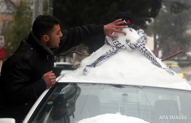 A Palestinian youth builds a snowman in the West Bank city of Ramallah as wintry weather swept through the region on March 2, 2012. Photo by Issam Rimawi