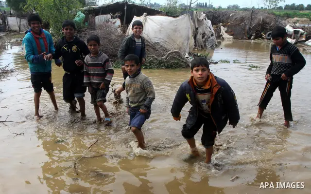 Palestinian Bedouin children walk through muddy waters after heavy rains which flooded the Al Moghraka area in the central Gaza Strip, 04 March 2012. Photo by Ashraf Amra