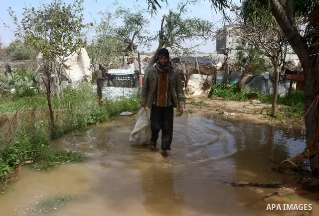 Palestinian Bedouin man walk through muddy waters after heavy rains which flooded the Al Moghraka area in the central Gaza Strip, 04 March 2012. Photo by Ashraf Amra