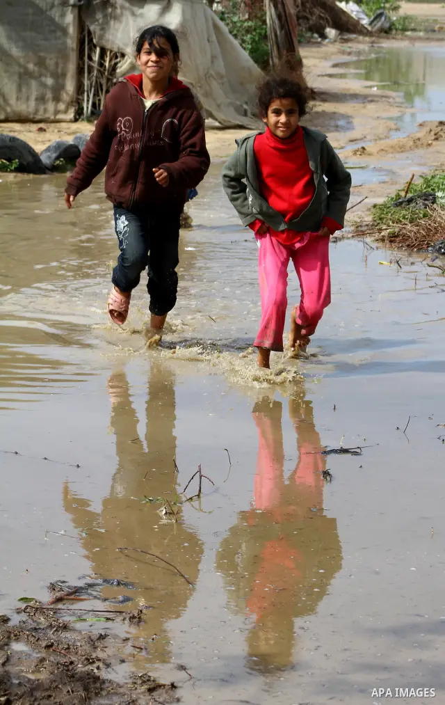 Palestinian Bedouin children walk through muddy waters after heavy rains which flooded the Al Moghraka area in the central Gaza Strip, 04 March 2012. Photo by Ashraf Amra