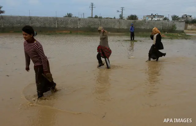 Palestinian Bedouin children walk through muddy waters after heavy rains which flooded the Al Moghraka area in the central Gaza Strip, 04 March 2012. Photo by Ashraf Amra