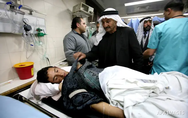 Palestinian paramedic examines a youth injured in an explosion, in the emergency room of a hospital in the West Bank city of Hebron March 6, 2012. Two Palestinian children were killed and three teenagers were injured whe...