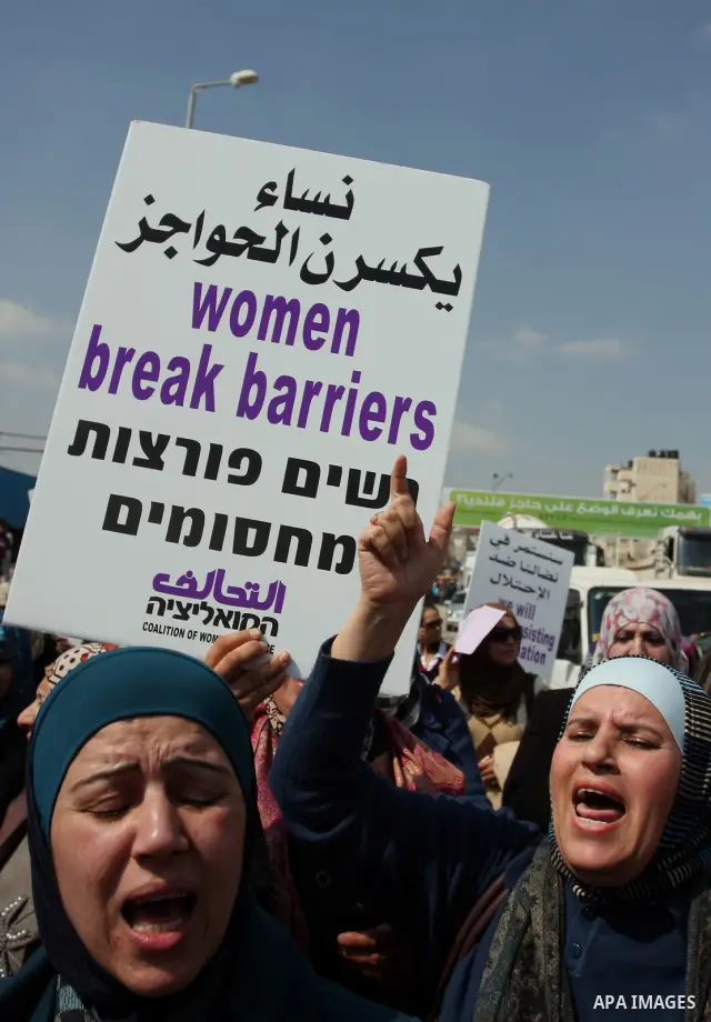 Palestinian woman shout slogans at Israeli soldiers while taking part in a demonstration to remove barriers on Palestinian land, to mark International Women's Day, on March 8, 2012, in the West Bank town of Qalandia. Pho...