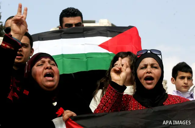 Women, holding Palestinian flags, shout slogans for the release of Hanaa al-Shalabi, a Palestinian woman freed in a prisoner swap with Israel but was re-arrested on February 16 2012, and has gone on hunger strike since,...