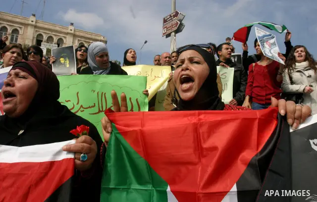 Women, holding Palestinian flags, shout slogans for the release of Hanaa al-Shalabi, a Palestinian woman freed in a prisoner swap with Israel but was re-arrested on February 16 2012, and has gone on hunger strike since,...