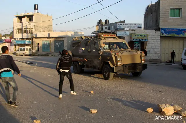 Palestinians throw stones at an Israeli military vehicle in the main street of the villlage of Yatta, south of the West Bank town of Hebron, after an Israeli soldier shot and killed a 17-year old Palestinian, Zakarya Abu...