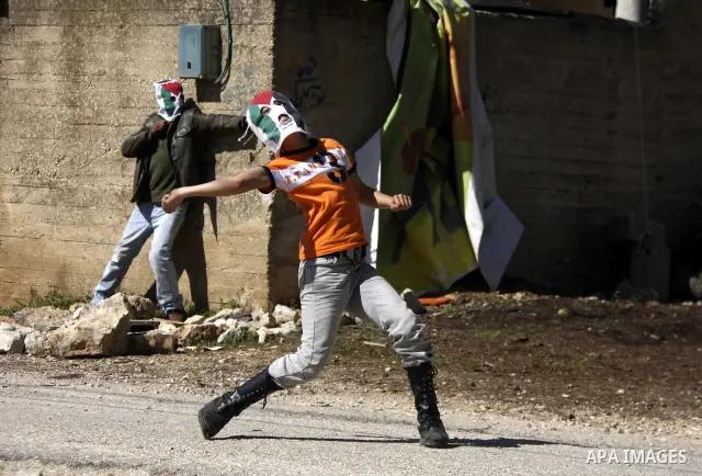 Palestinian youths hurlsl stones at Israeli security forces during a protest in the village of Kufr Qaddum near the Israeli settlement of Kdumim, in the northern West Bank, Friday, March 9, 2012. Photo by Wagdi Eshtayah