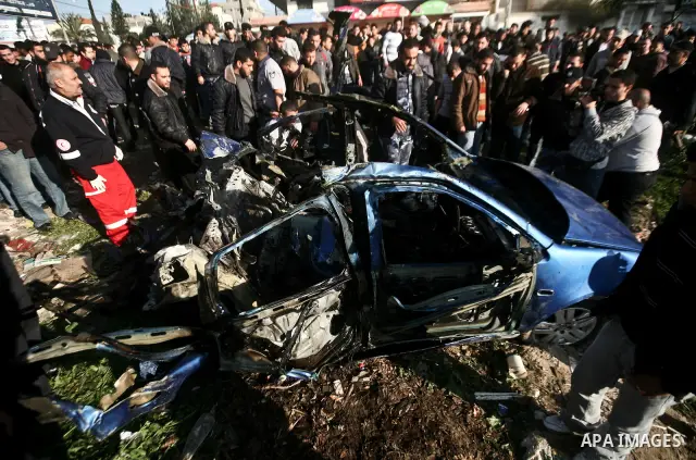 Palestinians look at the remains of a vehicle after it exploded in Gaza City March 9, 2012. Israel killed the leader of a Palestinian militant faction on Friday in a targeted attack on the car in the Gaza Strip, an Israe...