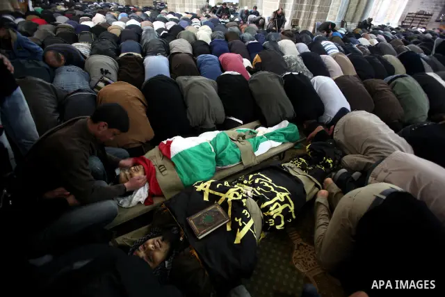 Palestinians pray near the bodies of Islamic Jihad militants during their funeral in Gaza March 10, 2012. Israel killed two more Gaza militants on Saturday, raising the death toll in two days of violence to 12 and dozens...