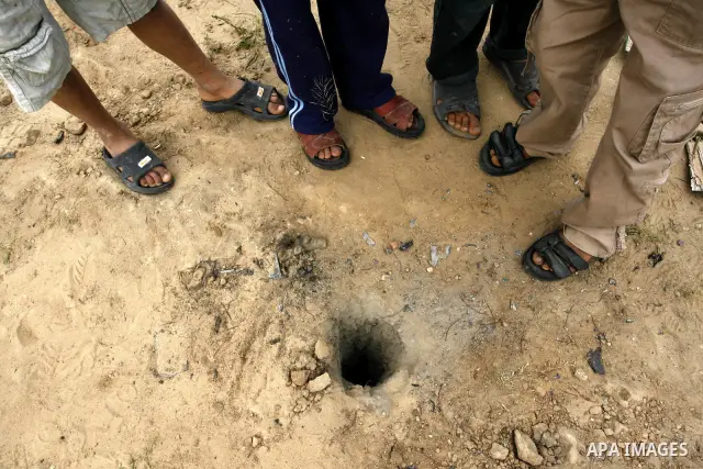 Palestinian boys look a damaged land following an Israeli air strike in Khan Younis in the southern Gaza Strip on March 12, 2012. Israeli air strikes killed two Palestinian militants and wounded 25 civilians in the Gaza...