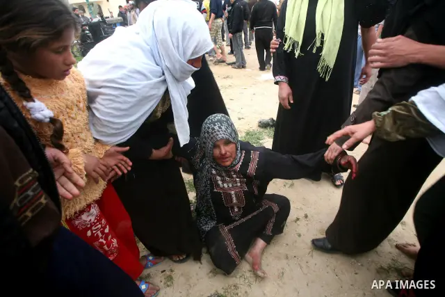 The mother of a Palestinian militant mourns next to his body (not seen) at the scene of an Israeli air strike in Khan Younis in the southern Gaza Strip March 12, 2012. Israeli air strikes killed two Palestinian militants...