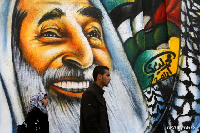 palestinians walk near of the mural of late Palestinian leader Yasser Arafat and late Hamas leader Sheikh Ahmed Yassin , in Gaza City on March 14, 2012. Photo by Ashraf Amra