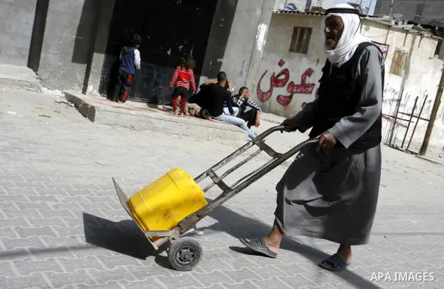 A Palestinian man filling plastic bottles and jerry cans with drinking water from a public tap at the United Nations Relief and Works Agency (UNRWA) headquarters in the southern Gaza Strip refugee camp of Rafah on March...